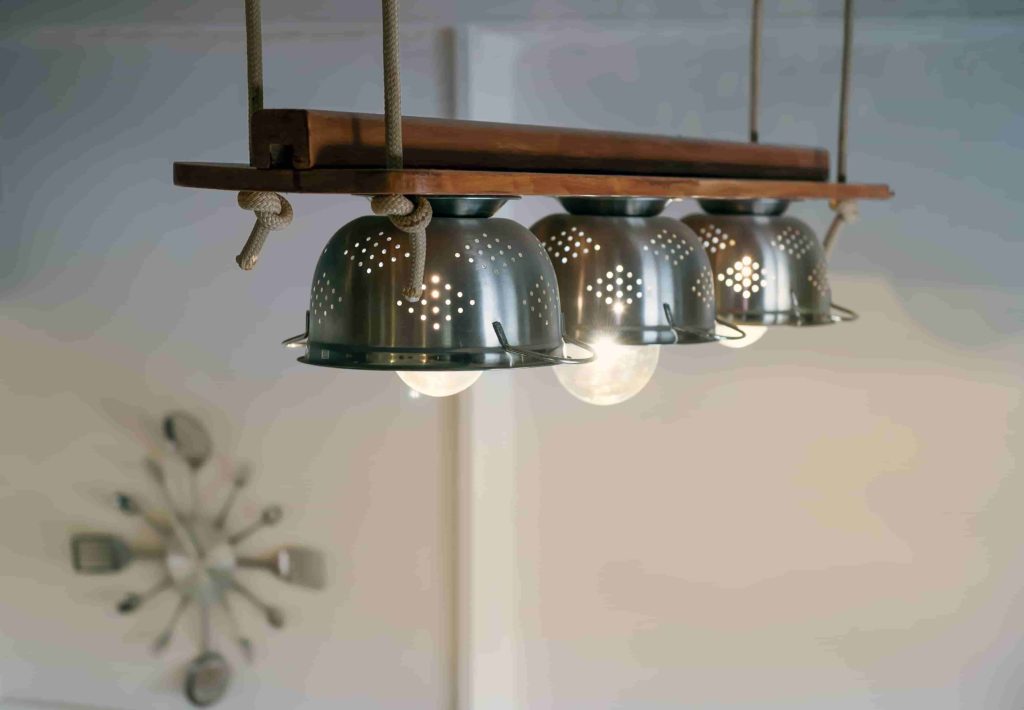 Warm lighting coming out from lamps inside beautiful utensils kitchen equipment, ropes and wood, hanged from the ceiling