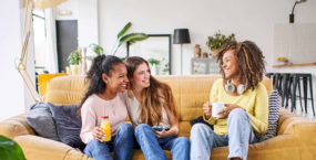 three-happy-female-friends-smiling-having-a-drink-on-sofa