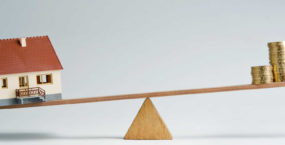 model-house-and-coins-balancing-on-seesaw-reflecting-inflation-5